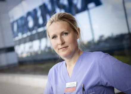 Forskare i läkarekläder framför Karolinskas fasad