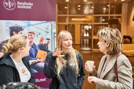 KI:s rektor fikar med studenter på en öppen yta inomhus.