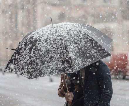 A man walking with an umbrella through a snow storm