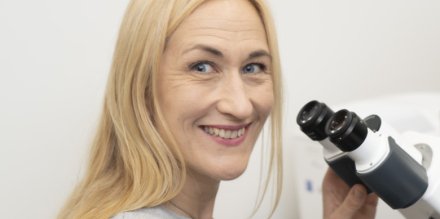Camilla Svenson in front of a microscope.