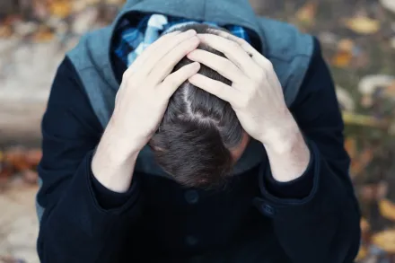 Photo of man holding his head in his hands.