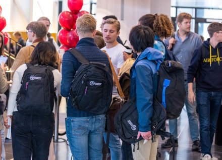 Studenter med KI-ryggsäckar framför ett bord under studiemässa.