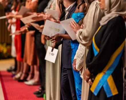 Hands of graduating students holding their diplomas in Aula Medica.