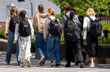 Personer, bakifrån, gåendes ute med KI-ryggsäck