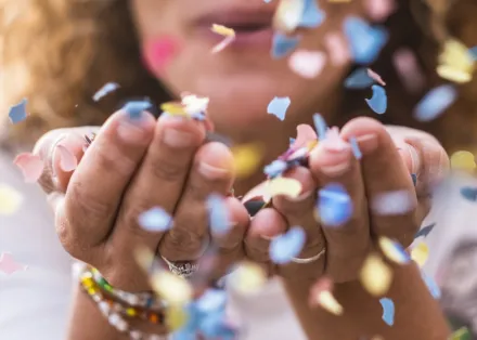Photo of woman blowing confetti.