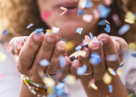 Photo of woman blowing confetti.