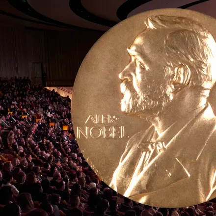 The Nobel prize medal with a background of an audience in the aula.